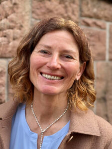 Freundlich lächelnde Astrid Hering vor einer Hausfassade